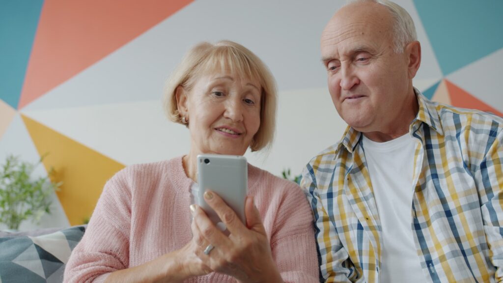 Elderly couple looking at a smartphone together. Best smartphones for seniors in 2025.
