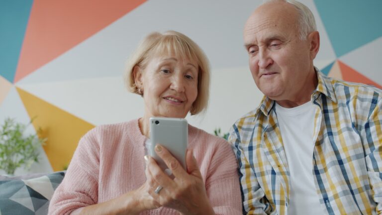 Elderly couple looking at a smartphone together. Best smartphones for seniors in 2025.