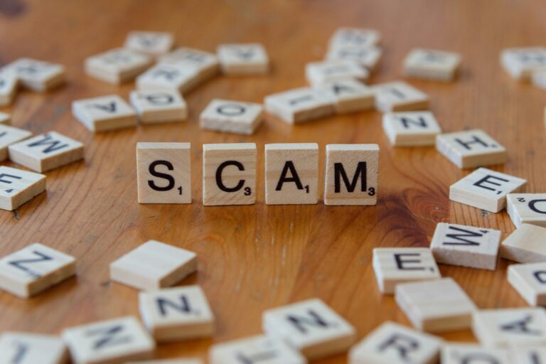 Scam spelled with scrabbles on a wooden table. Online scams targeting seniors.